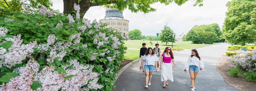  A view of the campus with the Nott Memorial prominently featured. Students stroll past a flowering bush on a warm, pleasant spring day.