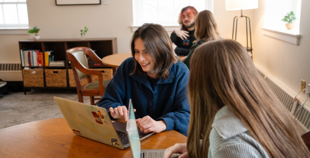 Students sitting at tables with their laptops at the Writing Center.